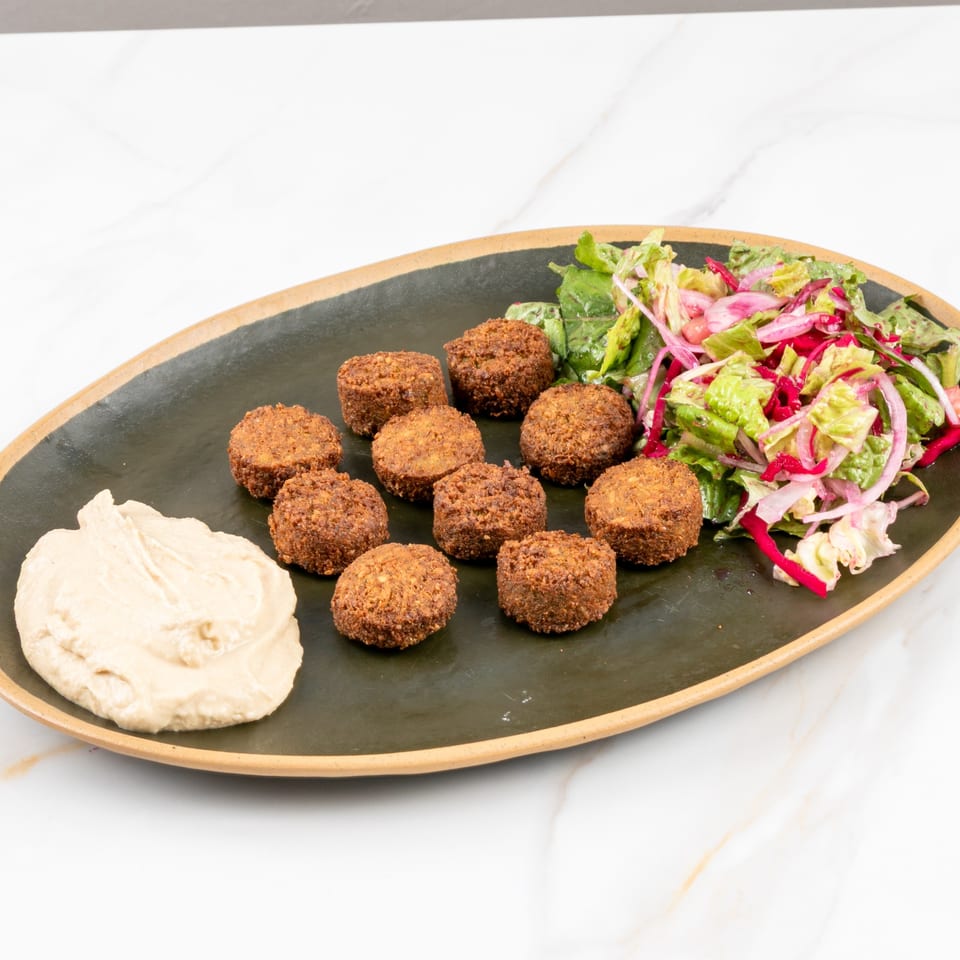 Marash Mediterranean falafel plate with hummus and a fresh salad of greens and red onions.