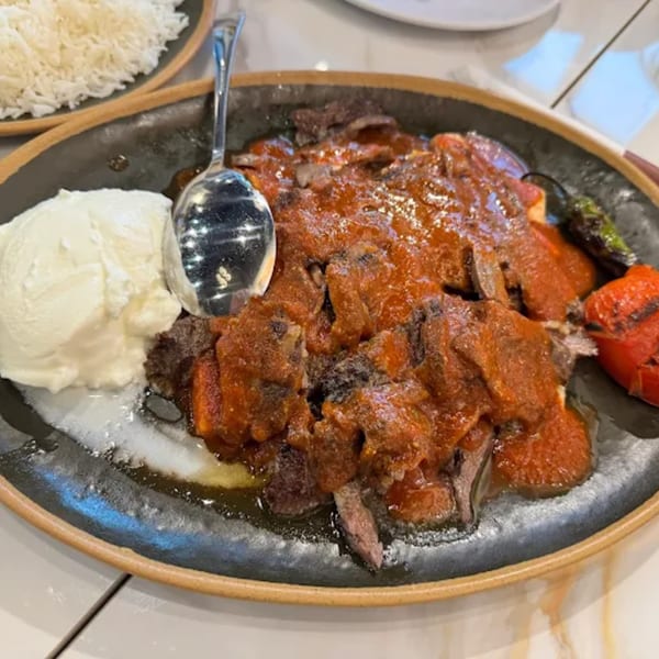 Iskender kebab with tomato sauce, yogurt, grilled pepper, and tomato, served with rice.