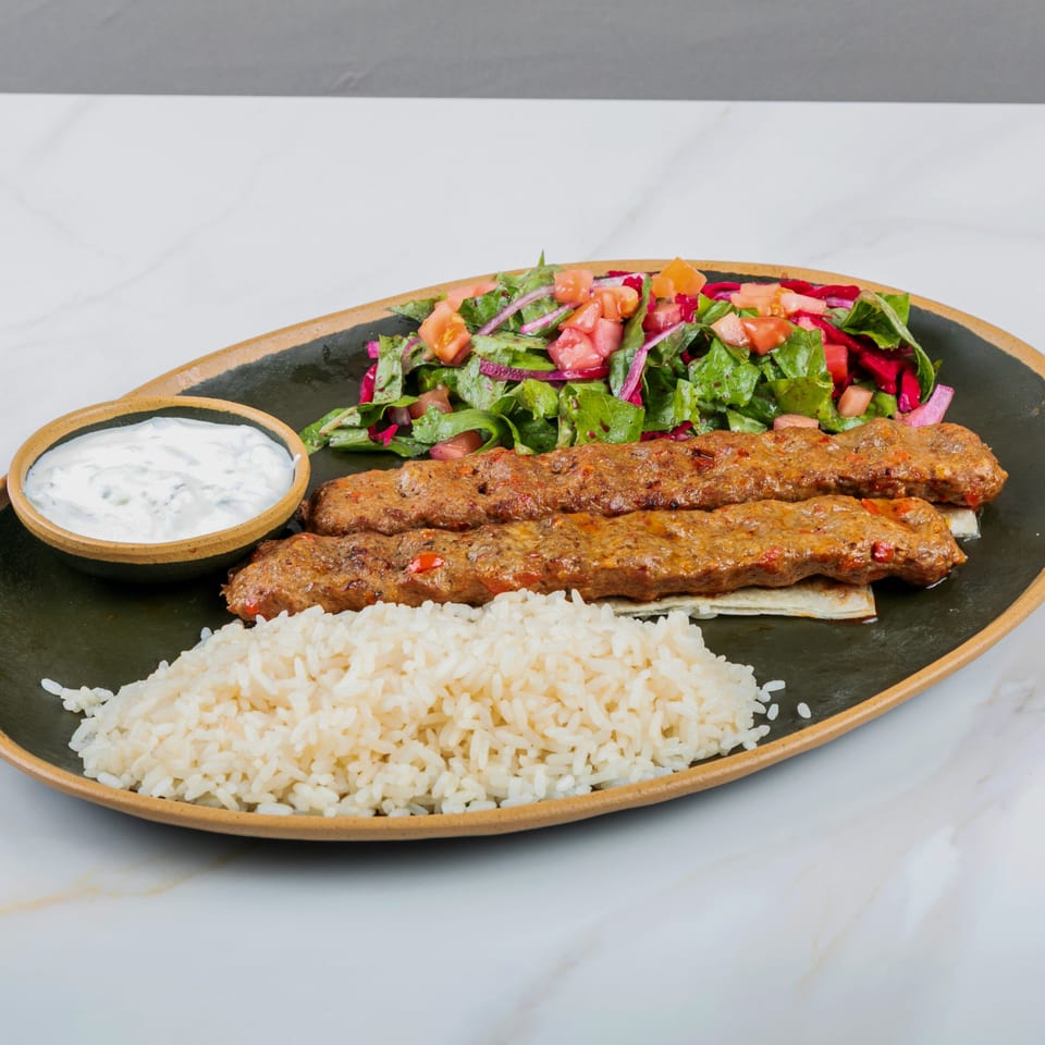 Marash Mediterranean Adana kebab with rice, salad, and a side of yogurt sauce.